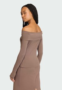 Off-the-shoulder brown top with long sleeves, fitted design, and smooth texture. Notable seam detailing along the back.