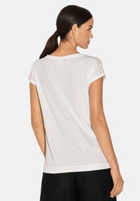 Weißes T-Shirt mit kurzen Ärmeln, rundem Halsausschnitt und umgeschlagenen Bündchen, glattes Material, lockere Passform und schlichtem Design. Keine sichtbaren Muster oder Akzente.