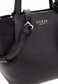Borsa nera realizzata in similpelle testurizzata. Presenta due manici, una tracolla rimovibile e accessori in oro con il nome del brand impresso sul davanti.