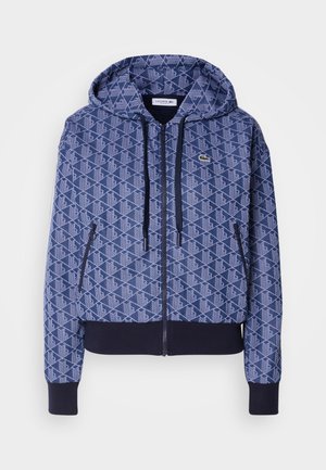 Felpa zip-up blu navy con motivo geometrico, tessuto morbido, polsini e fondo a costine di contrasto, cappuccio con cordino regolabile e dettaglio del logo.
