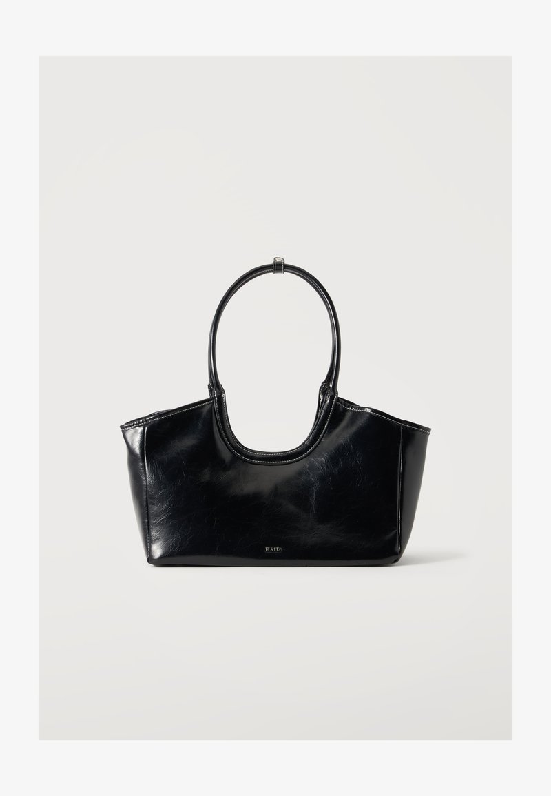 Sac à main en cuir noir brillant avec une grande poignée ovale et un logo subtil à l'avant sur un fond clair uni.