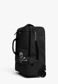 Bolsa de viaje negra con ruedas, fabricada con un material duradero, que presenta un gran gráfico de calavera y huesos cruzados, un asa superior y bolsillos laterales con cremallera.