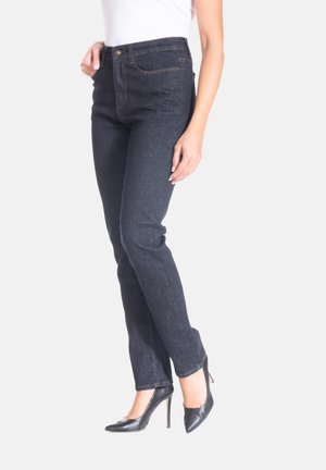 Jean en denim bleu foncé avec une coupe droite, dotés de poches latérales et de coutures décoratives. Portés avec des chaussures à talons hauts noires.