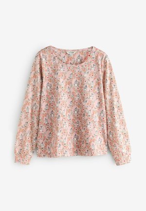 Ilgi piedurkņu krekls gaiši rozā audumā ar ziedu un varoņu rakstiem. Iekļauj apaļu kakla izgriezumu un savāktas aproces, lai piešķirtu tekstūru.