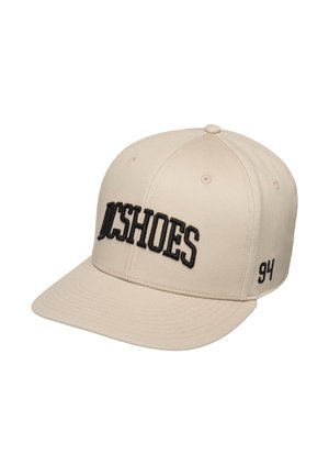 Beżowa czapka bejsbolowa z czarnym tekstem ""DCSHOES"" z przodu i ""94"" z boku, z przeszywanymi otworami wentylacyjnymi i płaskim daszkiem.