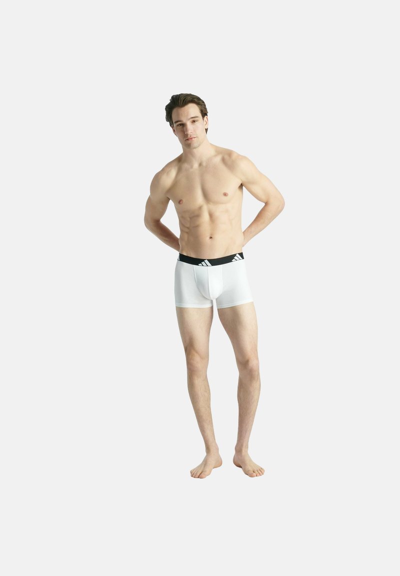 Vita boxershorts med ett svart midjeband som har en accentlogotyp. Materialet ser slätt och stretchigt ut, skräddarsytt för modellens kropp.