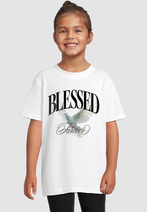 Jeune fille souriante aux cheveux attachés portant un t-shirt blanc avec une colombe blanche en vol et les mots "BLESSED Forever."
