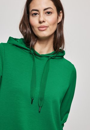 Grüne Kapuzenjacke mit lässiger Passform, strukturiertem Stoff, Kordelzugkapuze und schwarzen Metallenden. Einfaches Design und kräftige Farbe.