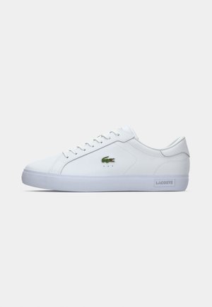 Adidași din piele albă, cu un profil redus, vârf rotund și talpă din cauciuc; prezintă un logo brodat verde pe lateral și o perforație minimă.