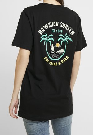 Black cotton t-shirt with a back graphic featuring palm trees, a sailboat, sun, and text "HAWAIIAN SURFER EST. 1986" and "The Island of Oahu."