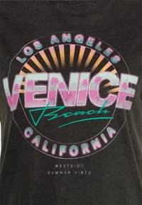 Grå t-shirt med en retro grafisk design och multicolorerad text: "VENICE Beach," "LOS ANGELES," och palmer.