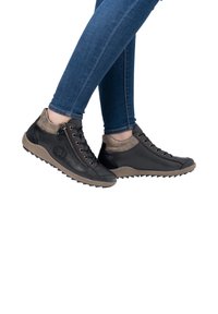 Chaussures montantes en cuir noir avec un col en daim gris, fermeture éclair sur le côté et lacets ronds ; semelle en caoutchouc brun texturé avec un motif de crampons agressif.