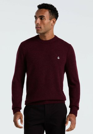 Bordeaux wollen trui met een geribbelde halslijn en manchetten, voorzien van een klein logo detail op de borst. Klassieke pasvorm en een gladde textuur.