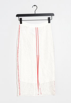 Witte kanten rok met een rekbare taille, voorzien van rode verticale strepen en franjerand onderaan. Hangt aan een zwarte haak.
