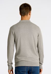 Grå tröja med krage, lång �ärm och ribbade ärmslut. Tyget har en slät textur och en figursydd design vid midjan.