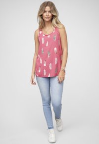 Roze mouwloos topje met veerpatronen; lichtgewicht stof; gecombineerd met lichtblauwe skinny jeans en witte sneakers; minimalistisch ontwerp.