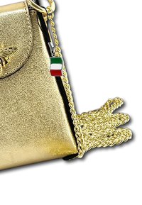 Goldene Lederhandtasche mit strukturiertem Finish, ausgestattet mit einer dekorativen Biene, goldener Kettenriemen und einem kleinen italienischen Flaggenanhänger.
