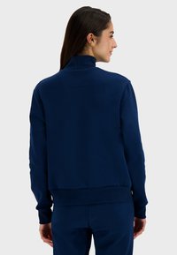 Navy blue sweatshirt with a high collar, textured fabric, ribbed cuffs, and hem, featuring a relaxed fit and minimal detailing.