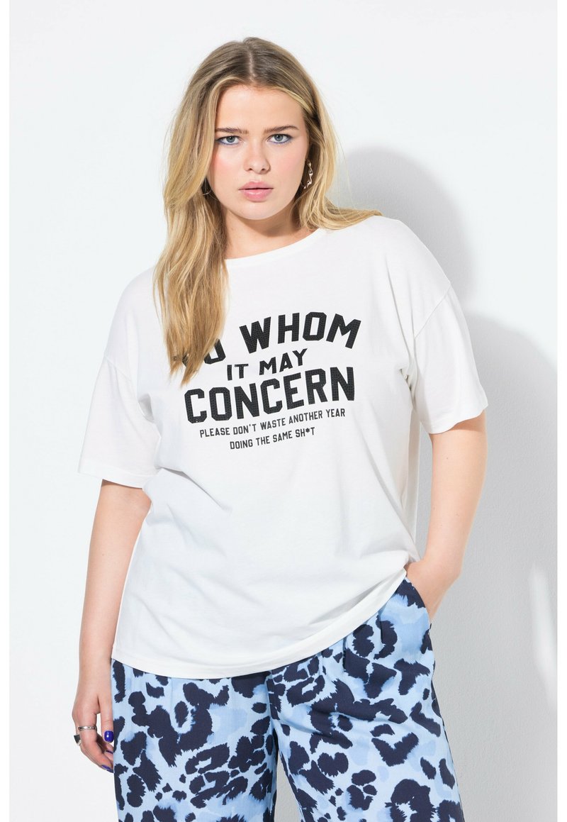 Witte katoenen T-shirt met gedurfde zwarte tekst, ronde halslijn en ontspannen pasvorm. Gecombineerd met blauwe broek met luipaardprint.