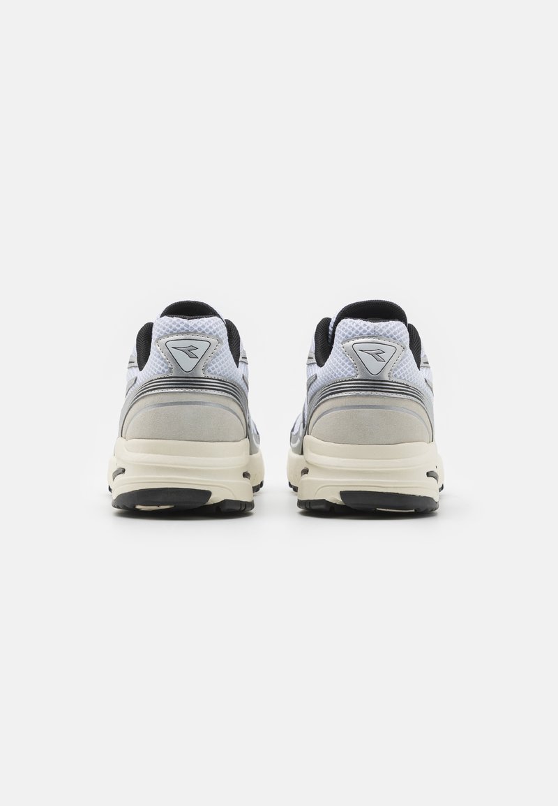 Scarpe sportive grigie e bianche con tomaia in rete, collare imbottito e suole scure. Dettagli del marchio sul tallone. Forma arrotondata, texture liscia.