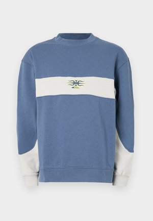 Sweatshirt bleu et blanc avec un col rond, des manches longues, et un motif central en jaune et vert foncé, avec des panneaux latéraux contrastants.