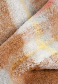 Vlněná tkanina s jemnou texturou, s kostkovaným vzorem v odstínech hnědé, bílé a akcenty žluté a světle růžové.