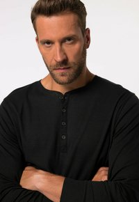 Musta pitkähihaisen henley-paita, jossa on ribbikuvio, napitettava etuluukku ja pyöreä kaula-aukko.