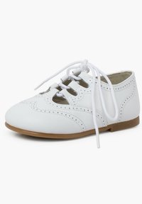 Scarpa in pelle bianca con punta tonda, fori decorativi e design con lacci. Presenta una suola piatta marrone e lacci bianchi.