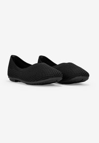 Ballerine nere in maglia con punta affusolata e superiore testurizzato, dotate di una suola elastica in gomma nera e senza hardware visibile.