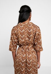 Jurk met patroon in bruin en crème slangenprint, korte mouwen, een kraaghals en een getailleerde taille voor vormgeving.