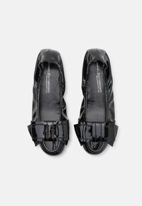 Ballerines en cuir verni noir avec un design plissé et un grand nœud structuré en accent au niveau des orteils. Doublure intérieure lisse.