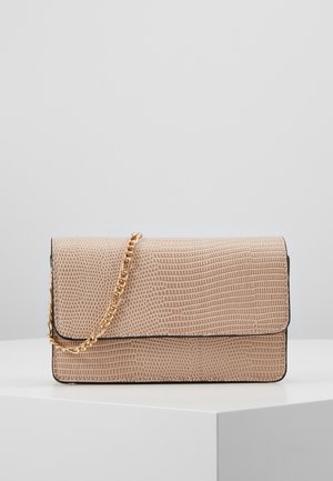 Pochette beige texturée avec un rabat et une chaîne dorée, exposée sur un piédestal blanc contre un fond neutre.