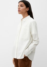 Witte button-up shirt van katoen, met een borstzak, lange mouwen en een relaxte pasvorm. Gestyleerd met bruine broek.