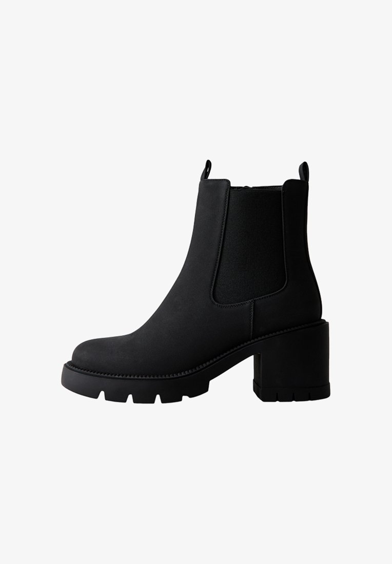 Stivale alla caviglia nero con tacco a blocco robusto, pannelli laterali elastici e finitura opaca liscia. Presenta una punta tonda e una suola testurizzata.