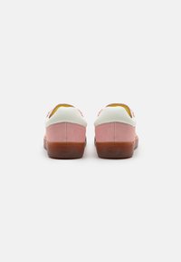 Zapatillas bajas con un cuerpo de ante rosa, acentos de cuero blanco y una suela de goma translúcida. Forma redondeada con un talón acolchado.