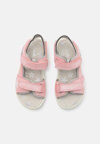 Vaaleanpunaiset taaperokenkä sandaalit, joissa on kaksi tarranauhaa, pehmeä kangaspinta ja pehmustettu pohja, jossa on tähtikuvio. Kiinni oleva kärki.