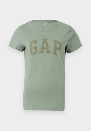 Maglietta a maniche corte di colore verde chiaro con scollo rotondo e grande logo "GAP" in lettere maiuscole di un verde tenue sulla parte anteriore.