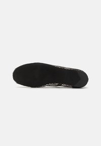 Suela de zapato negra con una superficie texturizada, que presenta un diseño de malla a lo largo de los bordes y un acabado mate suave en la parte inferior.