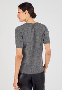 Maglione a maniche corte, con scollo rotondo, in maglia grigia melange. Bordo a costine sulle maniche e sull'orlo, texture morbida, silhouette aderente.