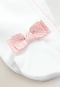 Biała skarpetka z małą, teksturowaną różową wstążką po boku, z przeszyciem wzdłuż górnej krawędzi.