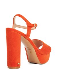 Orange suede high-heeled sandals featuring a platform sole, ankle strap with buckle, and a sculpted block heel. Gold hardware accent.