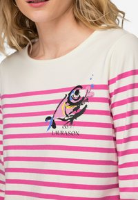 Camicia a maniche lunghe a righe con strisce orizzontali rosa, base color crema e stampa grafica di un pesce con accenti colorati e logo del marchio.