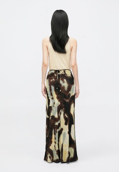 Abito lungo e aderente con un motivo astratto marrone e verde su un tessuto morbido, con una canotta beige visibile sopra il punto vita e un dettaglio con coulisse.