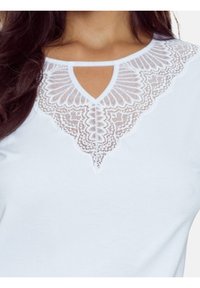 Biała bluzka z misternym detalem z koronki wokół dekoltu, z wycięciem w kształcie łezki. Miękka faktura i klasyczny design.