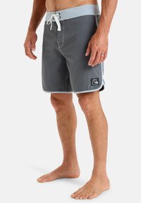 Gray swim shorts with a light blue waistband, white drawstring, side pockets, and a small logo patch on the lower leg.
