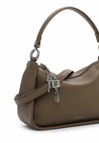 Brūna teksturēta ādas soma ar izliekta roktura, sudraba rāvējslēdzēja un trim sudraba logotipa piekariņiem, kas karājas uz ķēdes.