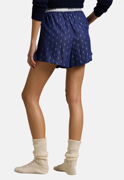 Marineblauwe shorts met een logo tailleband en subtiel paardenpatroon. Gecombineerd met witte geribbelde enkelkousen. Glad materiaal en losse pasvorm.