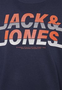 Maglietta blu navy con scritta audace in bianco e arancione "JACK & JONES", con motivo a puntini e strisce, in morbido cotone.