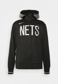 Veste zippée noire avec capuche, arborant "NETS" en grandes lettres blanches, logo Nike sur la poitrine gauche et accents gris sur la capuche et les manches.