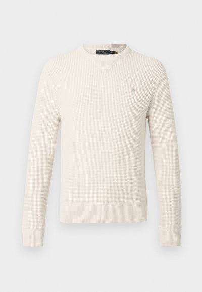 Ανοιχτό κρεμ πουλόβερ κατασκευασμένο από υφασμάτινη πλέξη με υφή, διαθέτει στρογγυλή λαιμόκοψη, μακριά μανίκια και ένα μικρό λογότυπο στο αριστερό στήθος.
